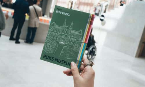 A visitor holding a printed museum guide booklet