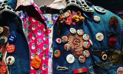 A denim jacket covered in collected pin badges