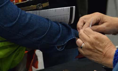 A staff member pinning a badge onto a guest's sleeve at check-in